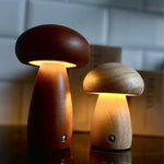 Load image into Gallery viewer, EcoMoshion wooden mushroom lamps in Nordic Beech and Deep Walnut finishes, glowing with warm light on a bedside table
